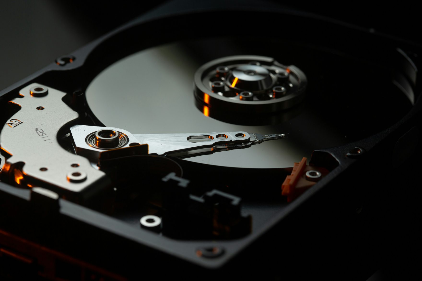 The exposed interior of a hard disk drive, its read arm resting across the mirrored platter
